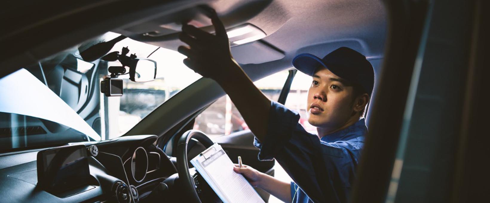 Mechanic doing a vehicle inspection inside a car Mechanic doing a vehicle inspection inside a car