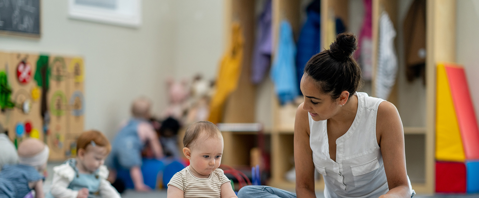 An ECE teacher is reading a picture book for a baby