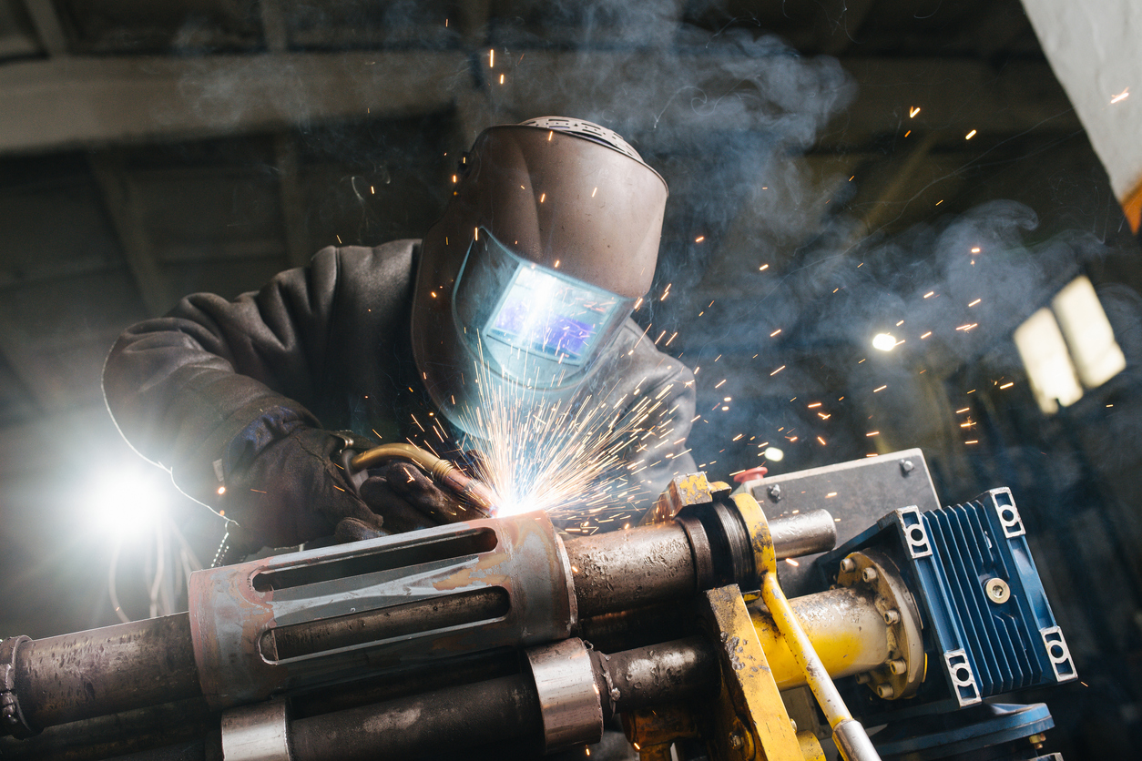 person welding metal together in an industrial warehouse  Introduction to MIG welding banner