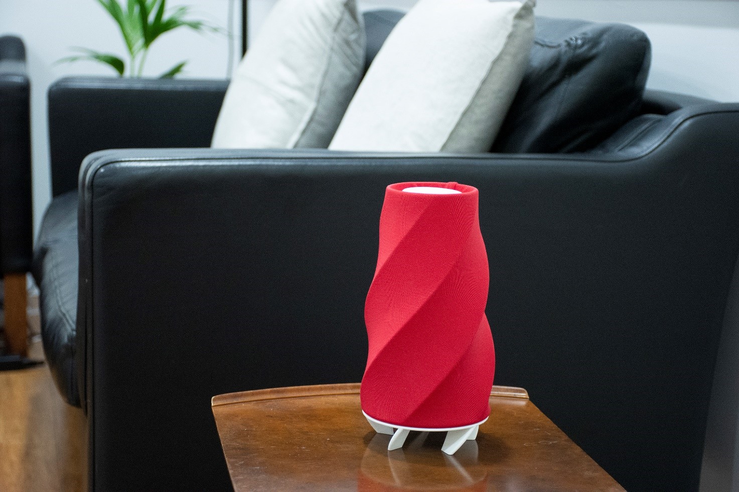 Internal air quality sensor that looks like a small table lamp stands on a coffee table in a lounge