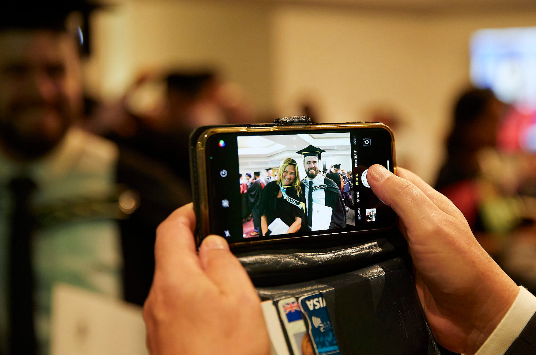 Picture of a phone screen where a photo is being taken of two people graduating