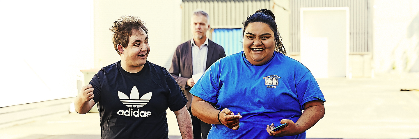 Supported Learning students walking together and smiling, their teacher in the background walking behind them