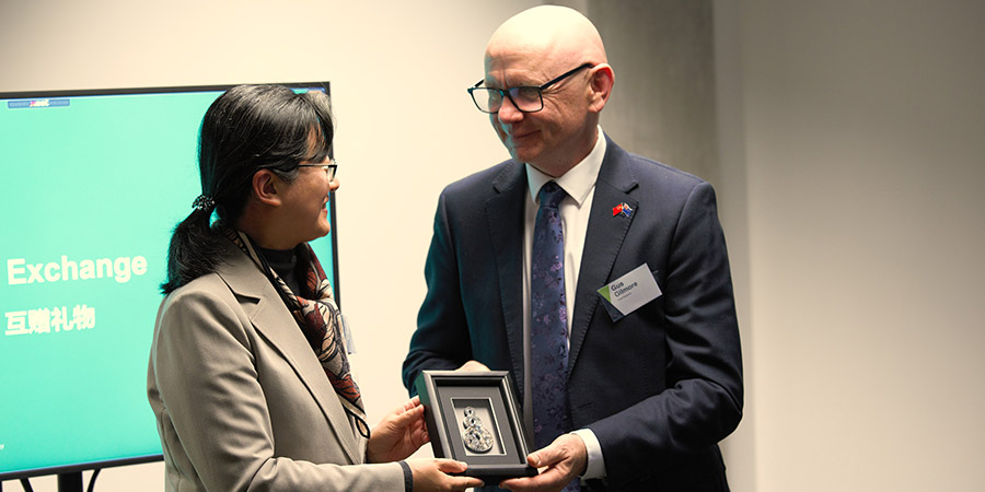 Gus Gilmore presents a gift of Māori carving taonga to Deputy Secretary General Yan