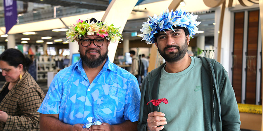 Two Unitec staff members happily pose showing the ei katu (head wreath of flowers) they created
