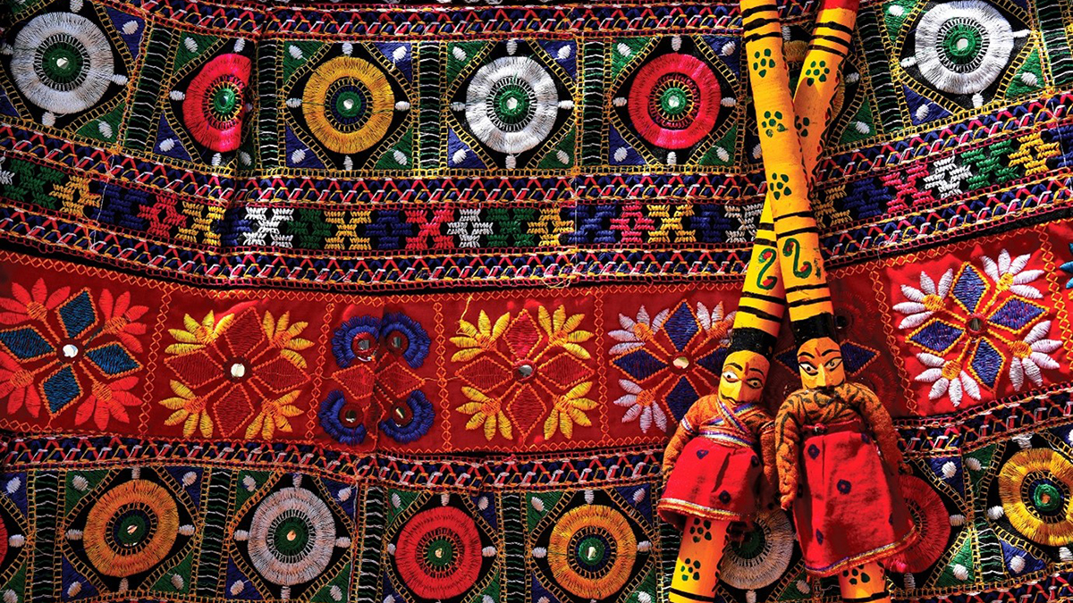 Vibrant tapestry with geometric patterns and floral motifs featuring two patterned dolls, symbolising cultural diversity and inclusive early childhood pedagogy.