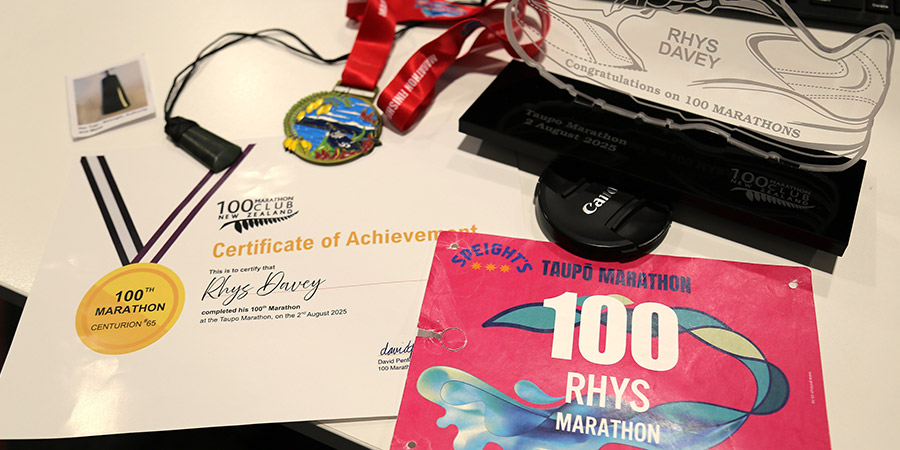 Rhys Davey's 100 marathon certificate, award and medal proudly displayed on his desk.