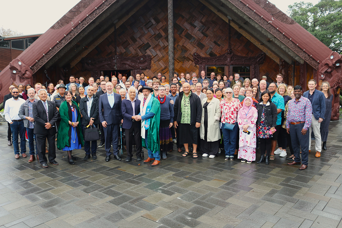 Group photo of over a hundred people—including past and present Unitec kaimahi, friends, and whānau—gathered at Te Noho Kotahitanga Marae to celebrate Marcus Williams being awarded the honorary title of Emeritus Professor.