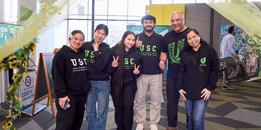 Five Unitec staff pose smiling in a group shot during Unitec open day