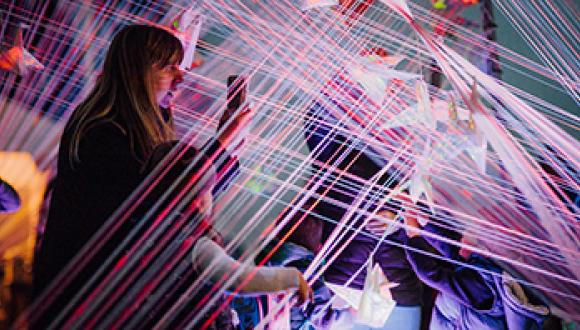 Visitors interact with a glowing architectural light installation during Matariki Market Night.