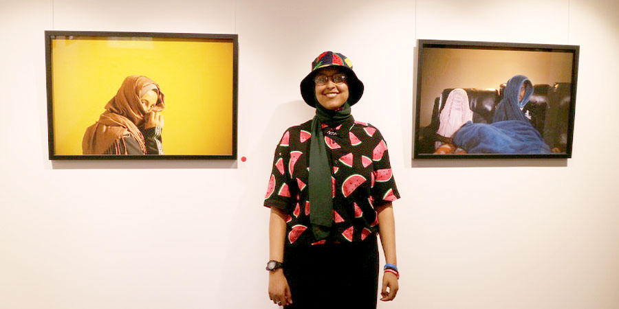Saynab Muse in front of two of her photographs.