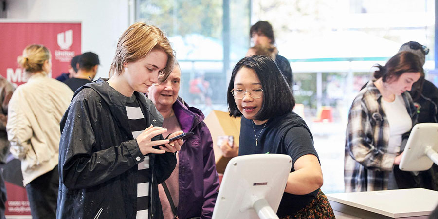 A volunteer helps a prospective student at open day.