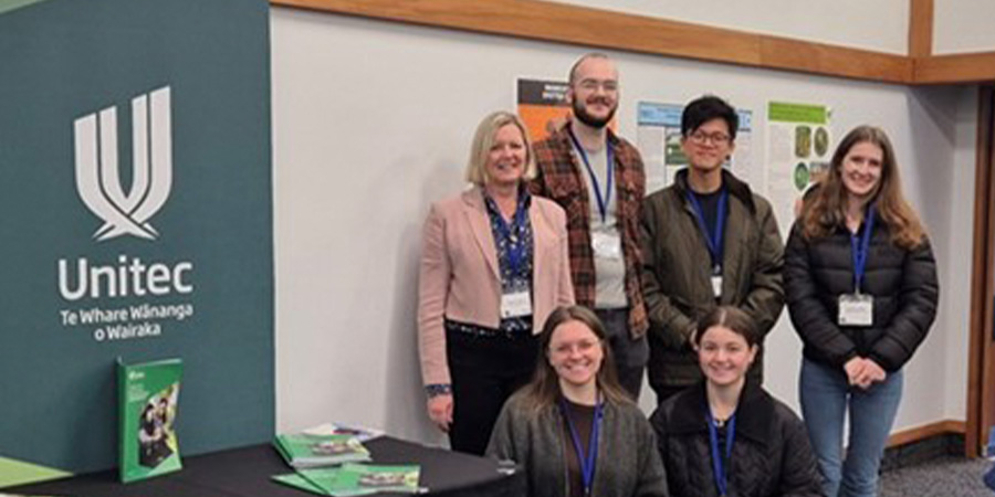 Five of Unitec's biosecurity ākonga along with one of their tutors in front of a Unitec banner.