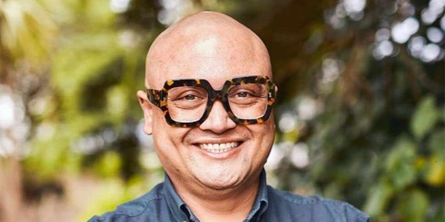 Byron Ranginui smiling outside, wearing glasses with a thick black frame.