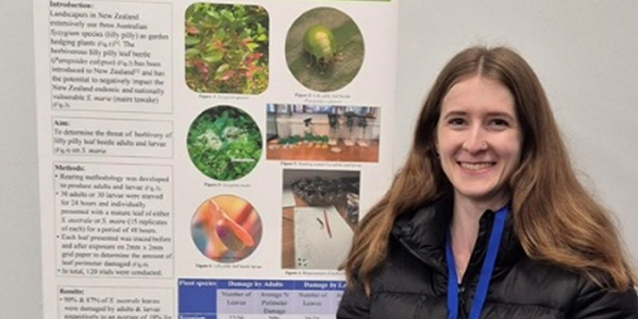 Jemma Owen stands in front of a poster giving information about biosecurity.