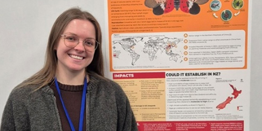 Taylor Devonshire in front of a poster giving information about biodiversity. 