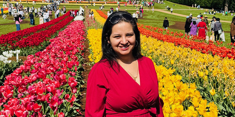 Parul Sharma in a sunny field of colourful flowers.