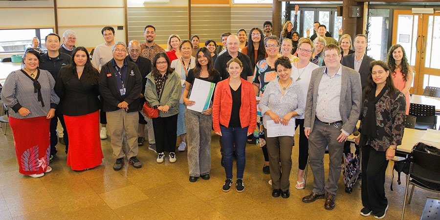 The competitors and judges from the Three Minutes to Impact research presentation competition stand smiling in a group.
