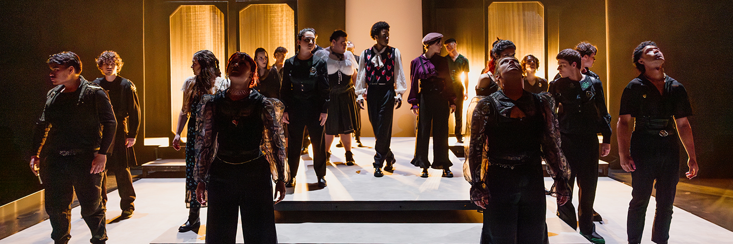 Acting for Screen and Theatre students pose in a moody backlight stage environment