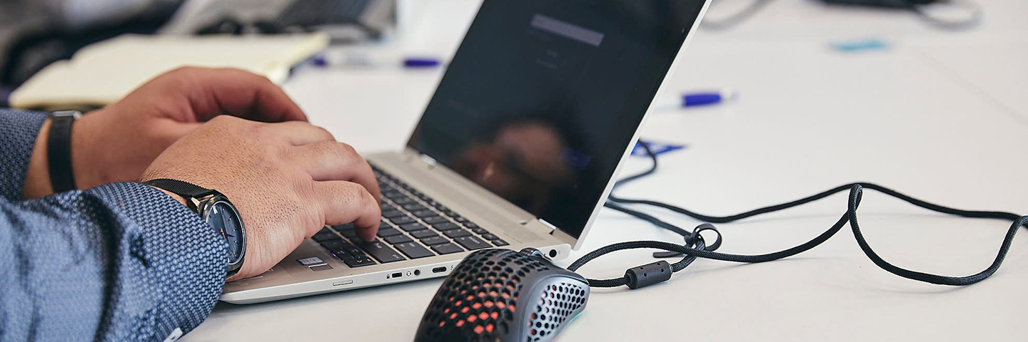 person logging in to laptop that sits on top of a white desk