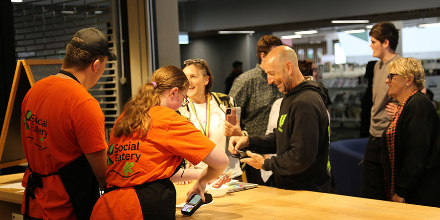Students serve food to happy customers at the Social Eatery.