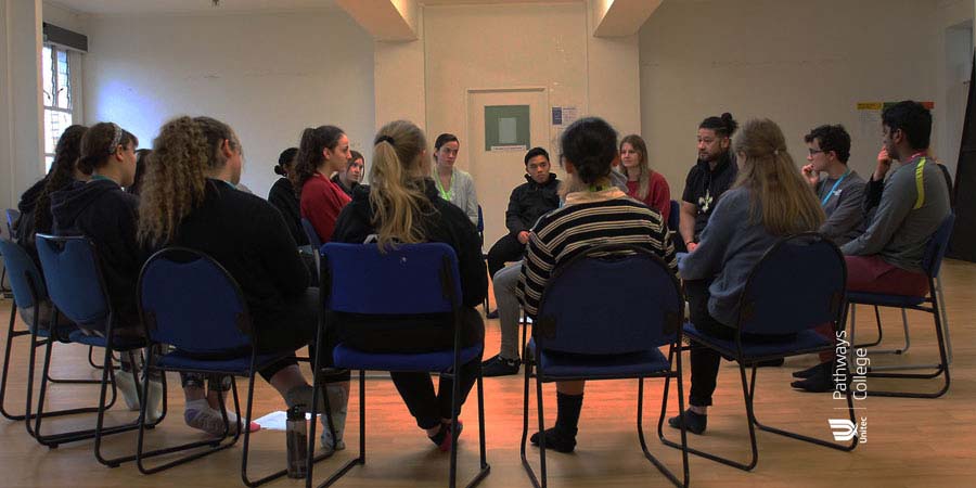 A group of students sit in a circle on chairs.