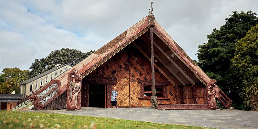 A wahine Māori waits at the entrance of the Te Noho Kotahitanga wharenui to greet new arrivals onto the marae.