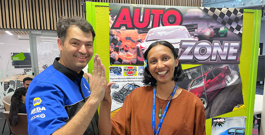 Two kaimahi high five while smiling for the camera.