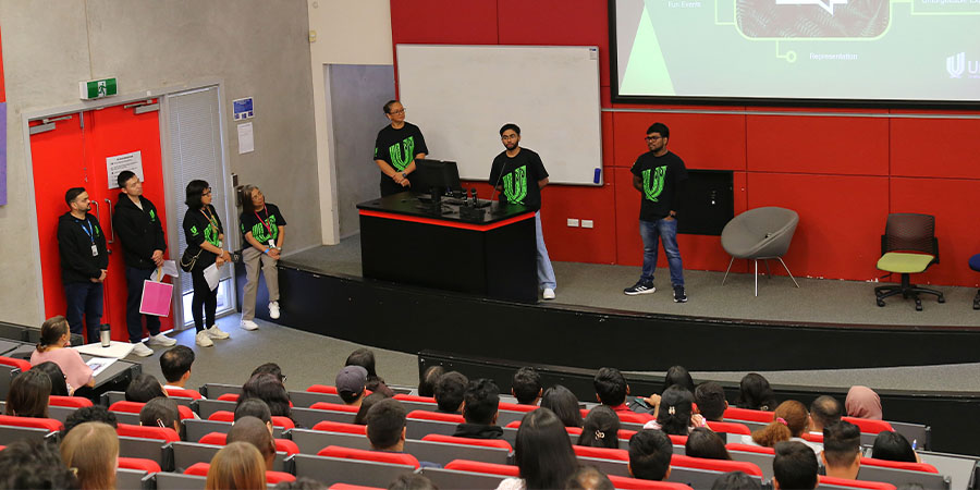 Unitec staff give a presentation to international students in a lecture theatre.