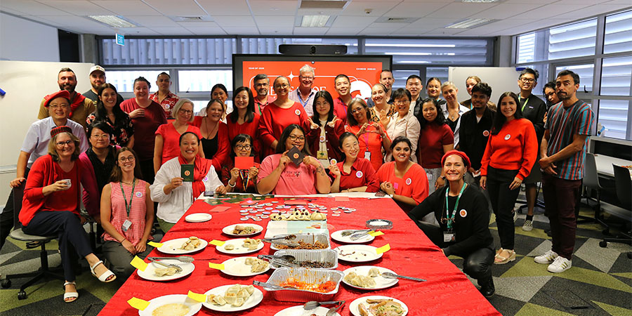 A large group of Unitec staff pose for a photo at the head of a table full of Chinese food.