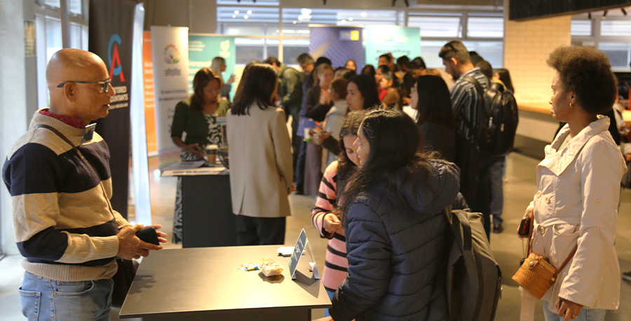 A company rep at a kiosk talks to students.