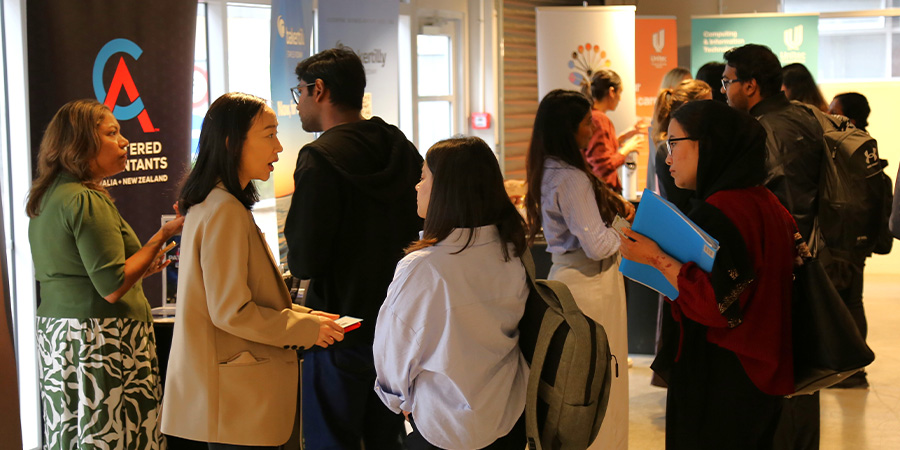 A company rep at a kiosk talks to students.