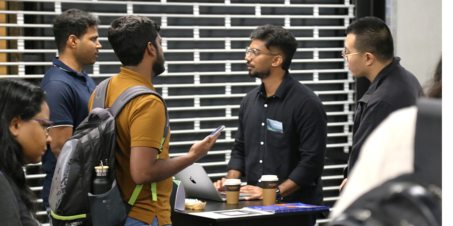A company rep at a kiosk talks to students.