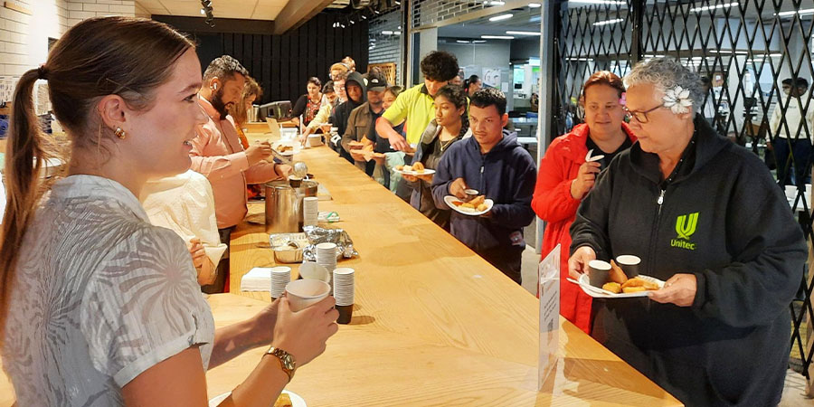 Students and staff move along a line of servers dishing out traditional food. 
