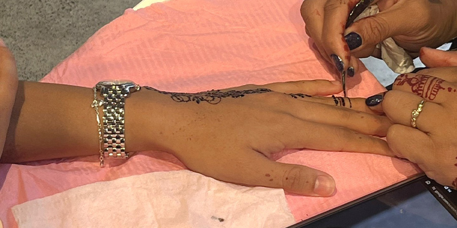 A close up of a hand being decorated with henna. 