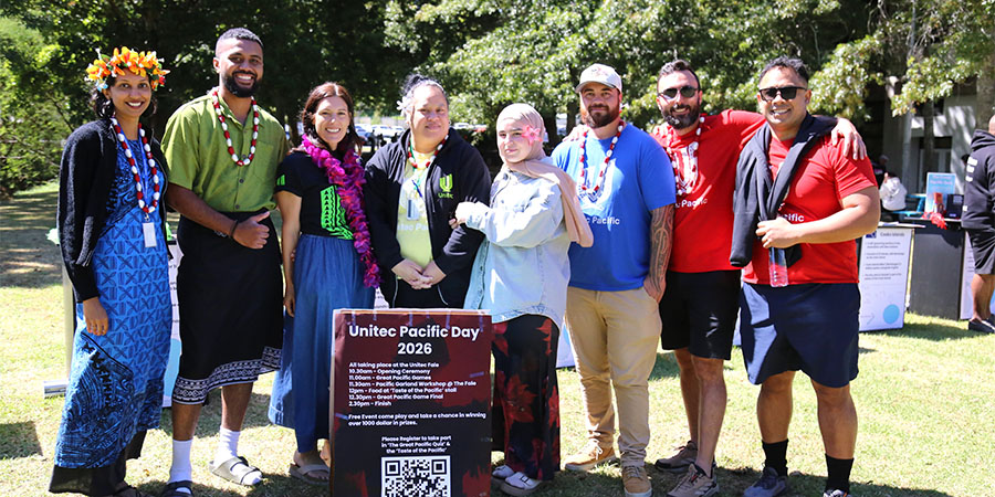 Pacific ākonga and kaimahi, some wearing traditional attire and garlands, pose for a photo.