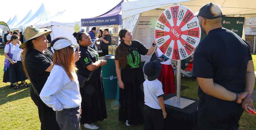 A group of people look at the 'winning wheel' to see what prize it has landed on.