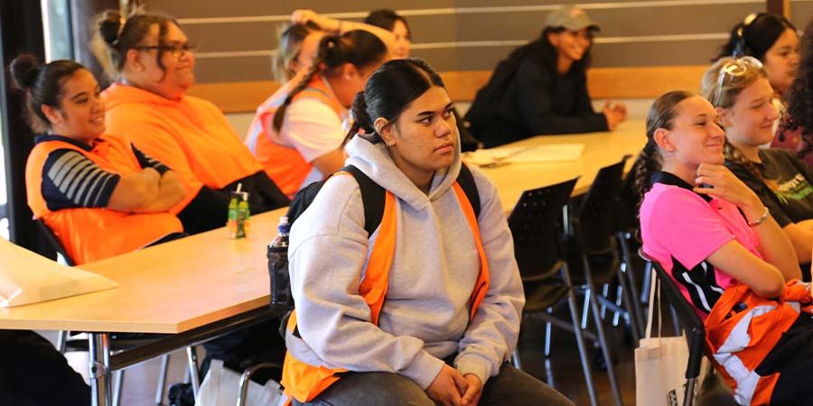 A group of women sit listening to a lecturer.