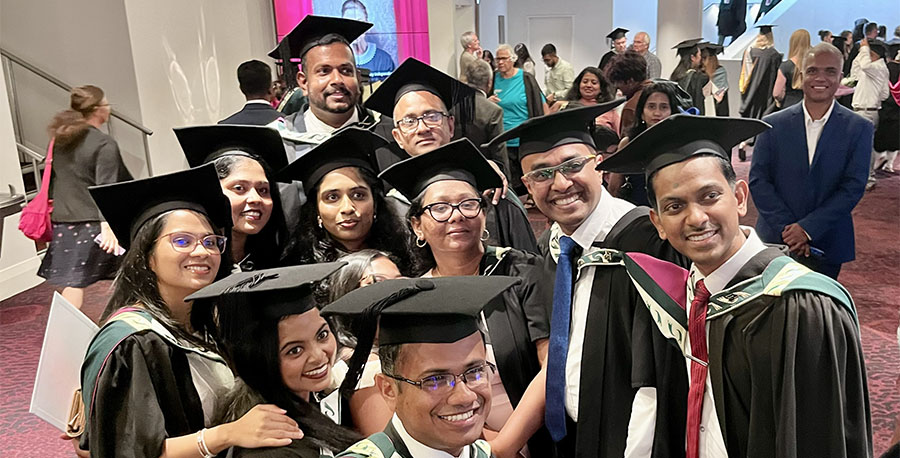 A group of graduates in regalia pose for a photo.