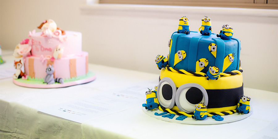 A 'Minions' themed cake and a pink woodland themed cake on a table.