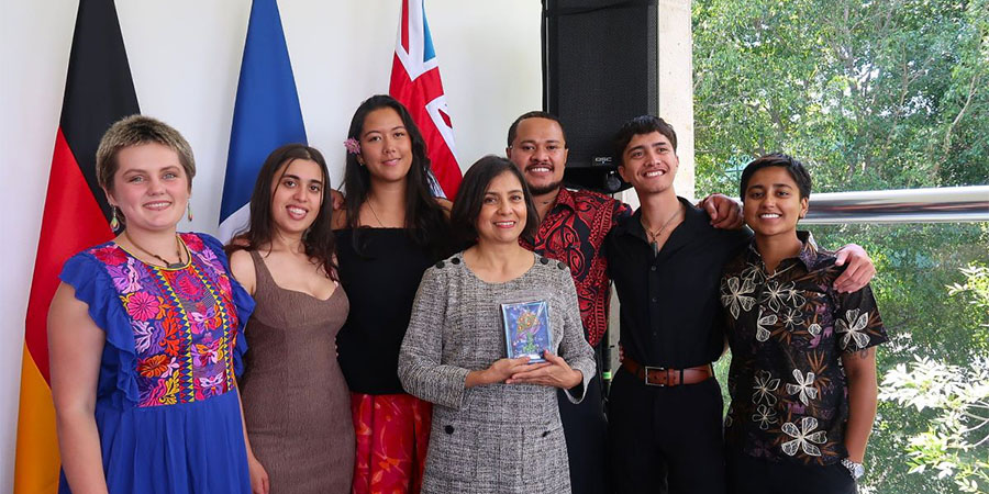 The scholarship winners smile for the camera in front of different country's flags.