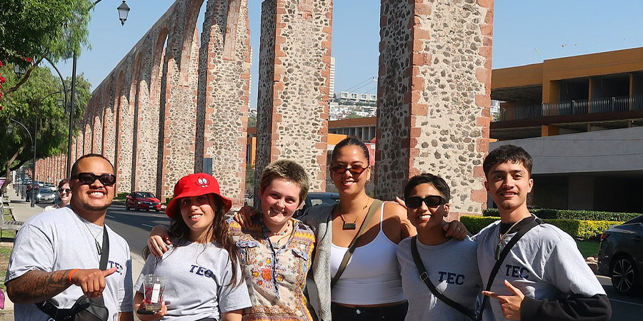 The scholarship winners in front of a large viaduct.
