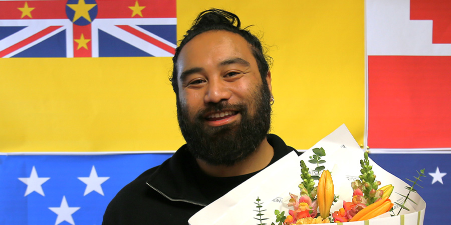 Michael Kapisi in front of various flags of Pacific nations.