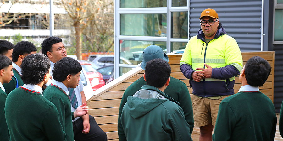 A lecturer talks to students outdoors on Mt Albert campus.