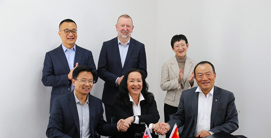 Professor Christina Hong shakes hands with one of the delegates from China, surrounded by MITU staff and the Chinese delegates.