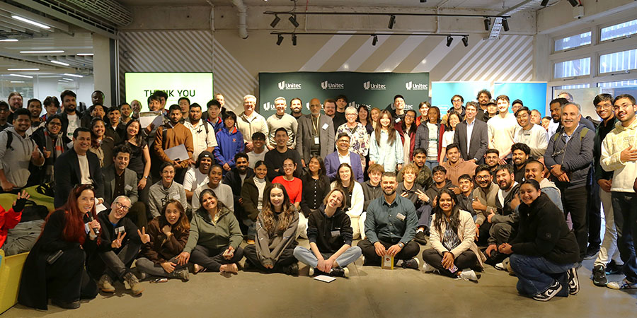 The assembled participants, mentors and judges smile for the camera in the Mt Albert campus events kitchen.