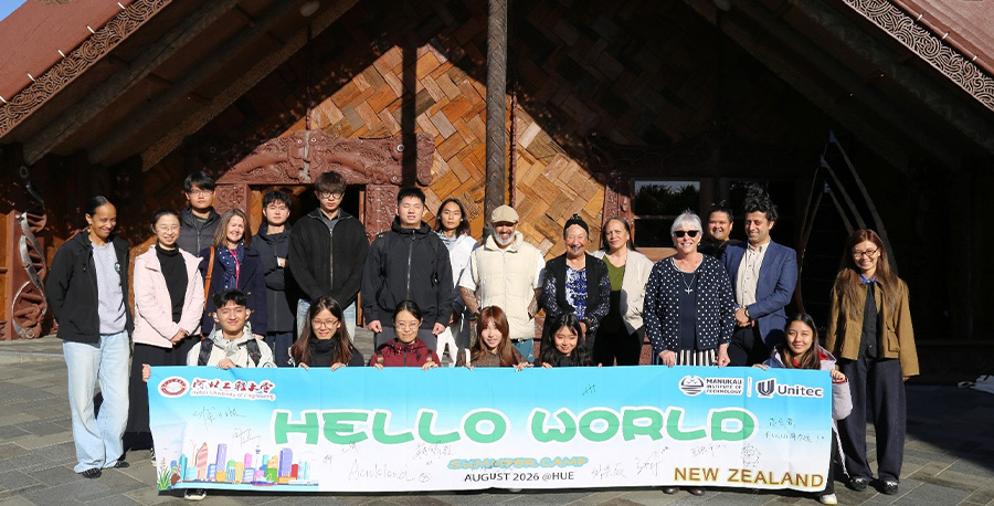 Exchange students and staff smile outside te wharenui o Te Noho Kotahitanga Marae.