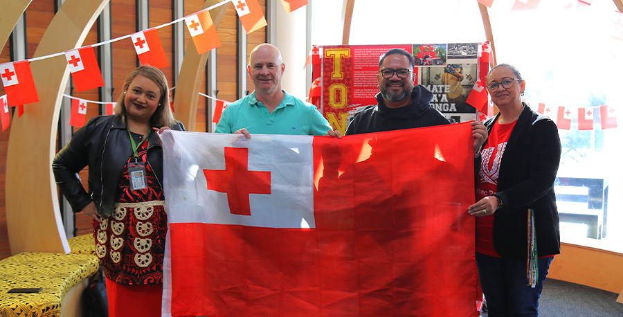 Tongan kaimahi Helena Finau-Hakalo, Jason Hallie, Ioane Aleke Faavae and Annette Pitovao proudly fly the Tongan flag at our Tongan Language Week display at our Ōwairaka I Mt Albert Campus