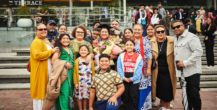 A family pose for a photo around a graduate in graduation regalia.