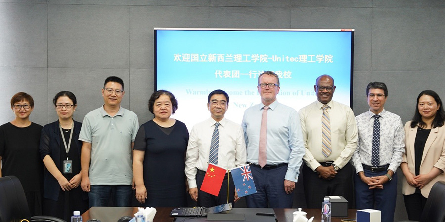Unitec and Shanghai Polytechnic University staff smile for the camera behind a table.