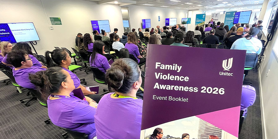 Staff and students in purple t-shirts listen to a talk at the Family Violence event.
